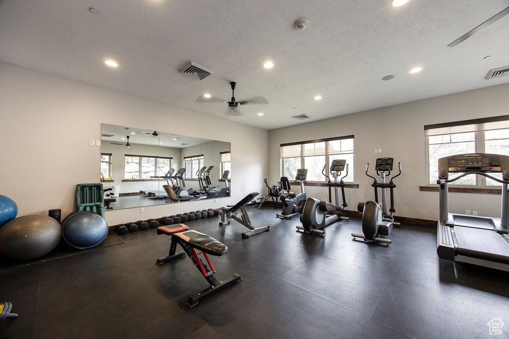 Gym featuring a ceiling fan, a textured ceiling, recessed lighting, plenty of natural light, and baseboards