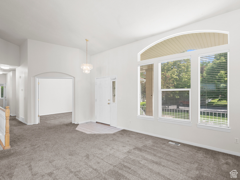 Foyer entrance with carpet floors, plenty of natural light, a chandelier, and baseboards