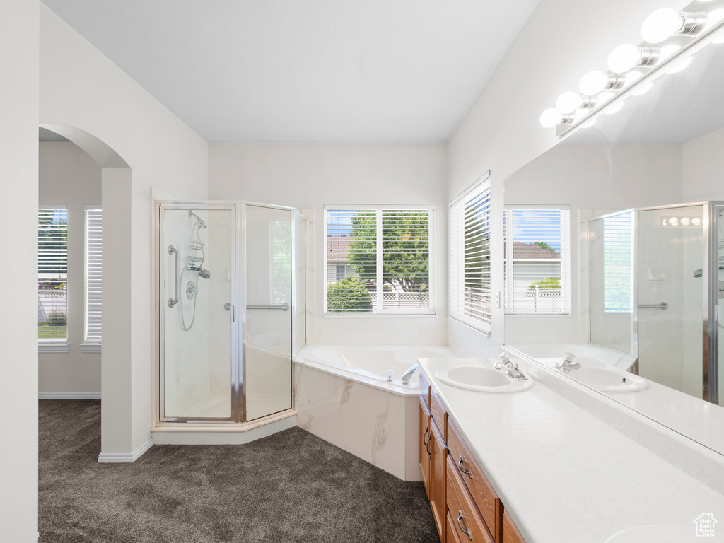 Bathroom with double vanity, a stall shower, a garden tub, and healthy amount of natural light