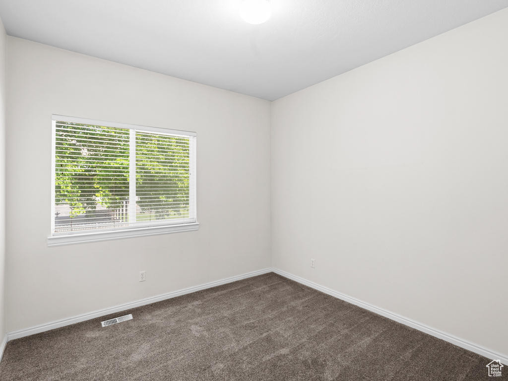 Unfurnished room with dark carpet and baseboards