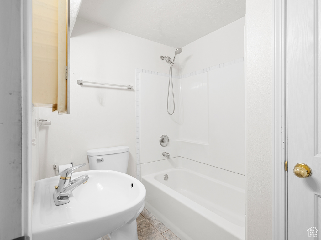 Full bath with a sink, shower / bath combination, toilet, and tile patterned floors