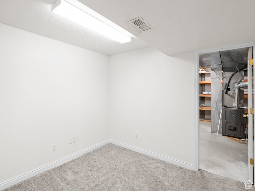 Finished basement with baseboards, carpet, and heating unit