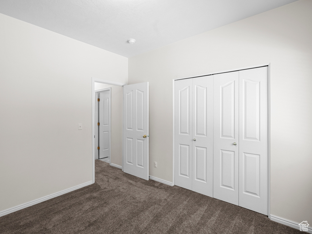 Unfurnished bedroom featuring carpet floors, baseboards, and a closet