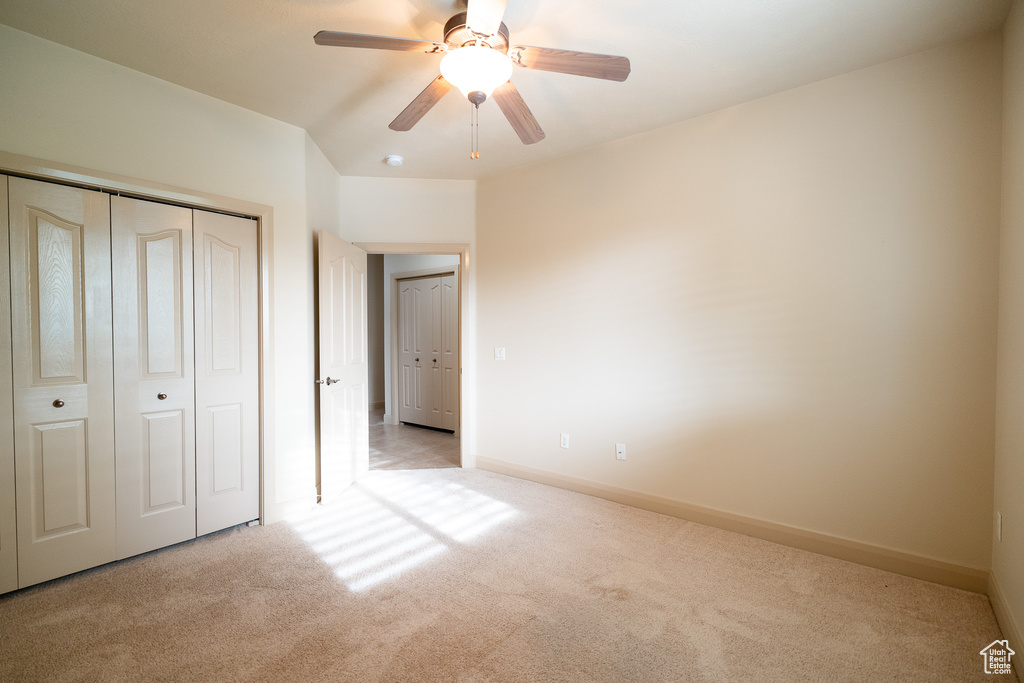 Unfurnished bedroom with carpet floors, a closet, baseboards, and a ceiling fan