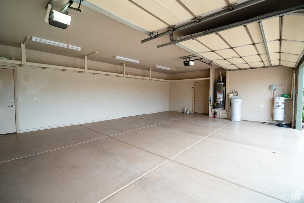 Garage featuring gas water heater, strapped water heater, and a garage door opener