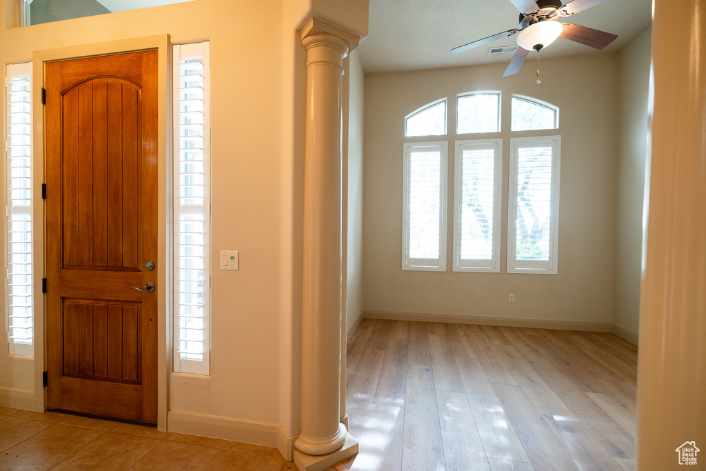 Foyer featuring ornate columns, baseboards, a ceiling fan, and light wood finished floors