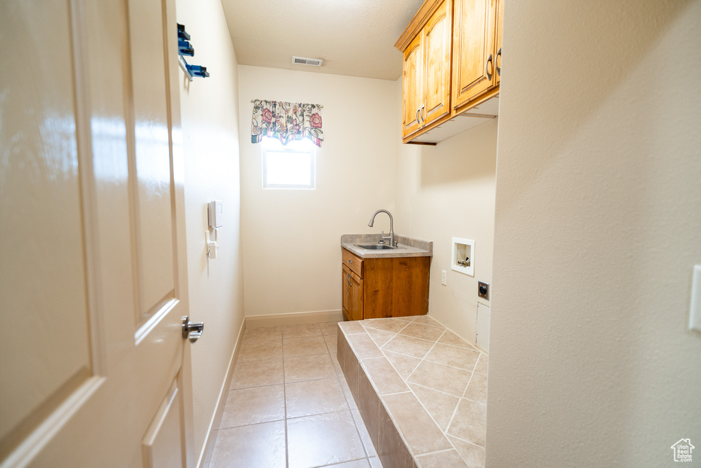 Laundry room with hookup for a washing machine, cabinet space, light tile patterned flooring, and baseboards