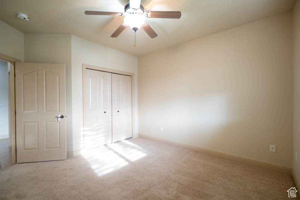 Unfurnished bedroom featuring carpet, a closet, baseboards, and a ceiling fan
