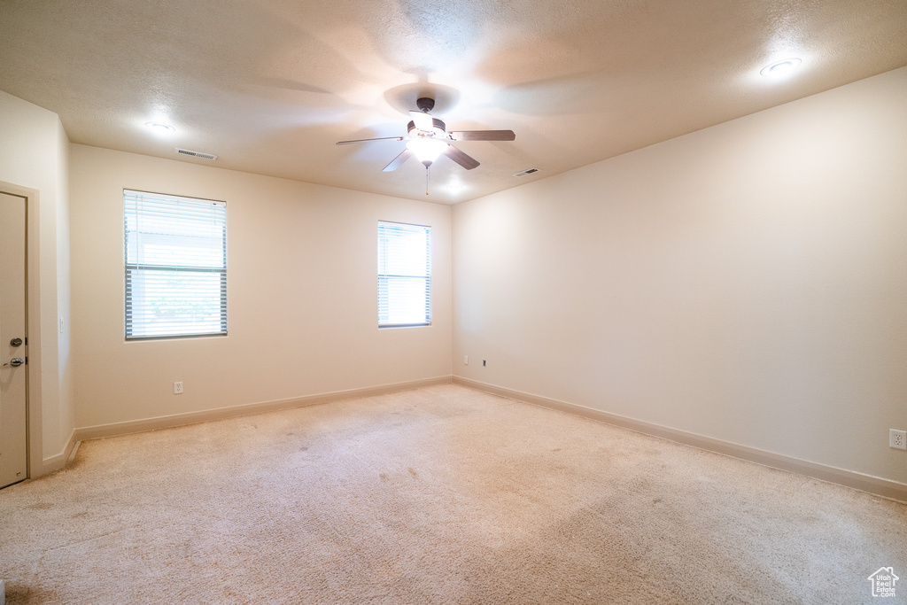 Empty room featuring light carpet, ceiling fan, and baseboards