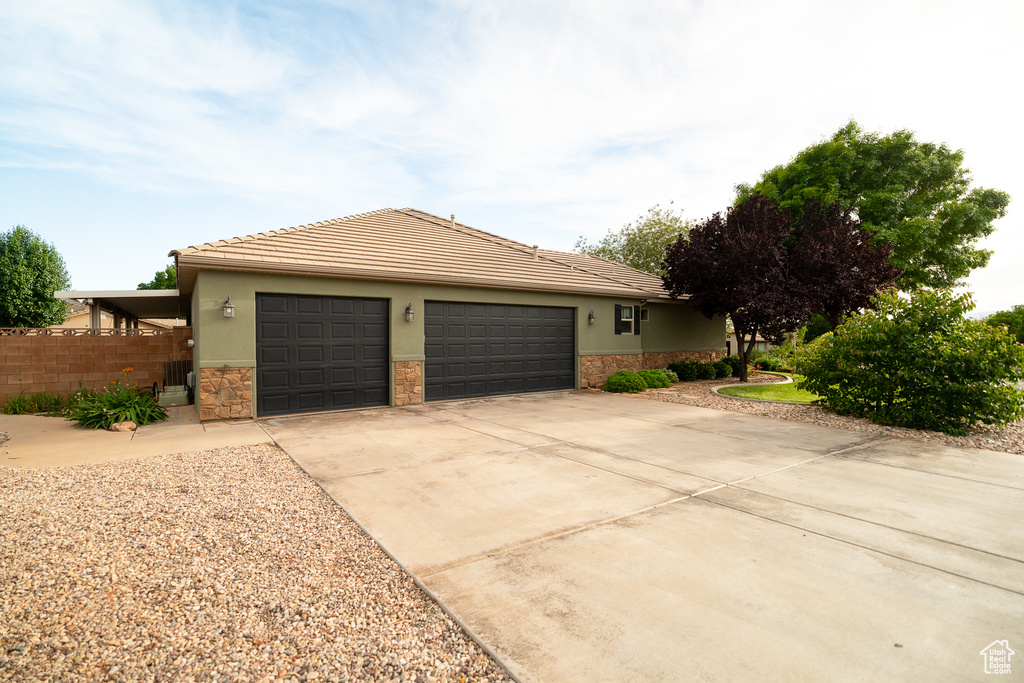 View of front of home featuring stone siding, a garage, driveway, a tile roof, and stucco siding