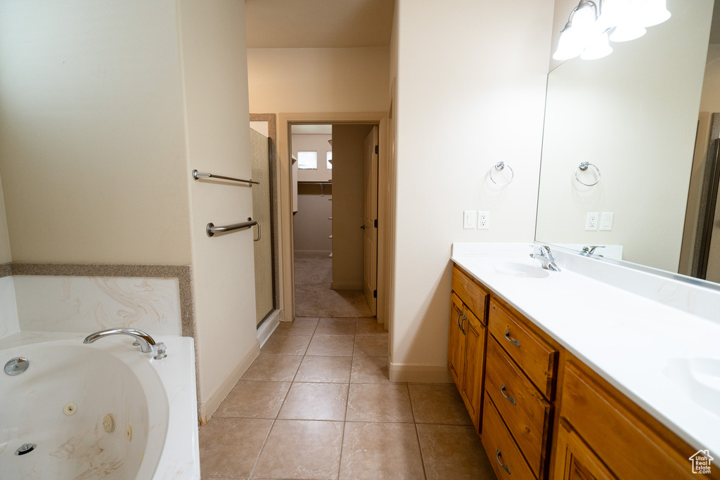 Bathroom with double vanity, a whirlpool tub, a stall shower, tile patterned floors, and baseboards