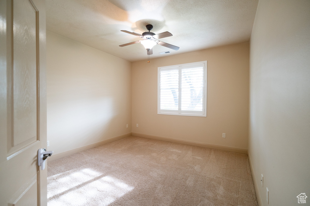 Carpeted empty room with a ceiling fan and baseboards