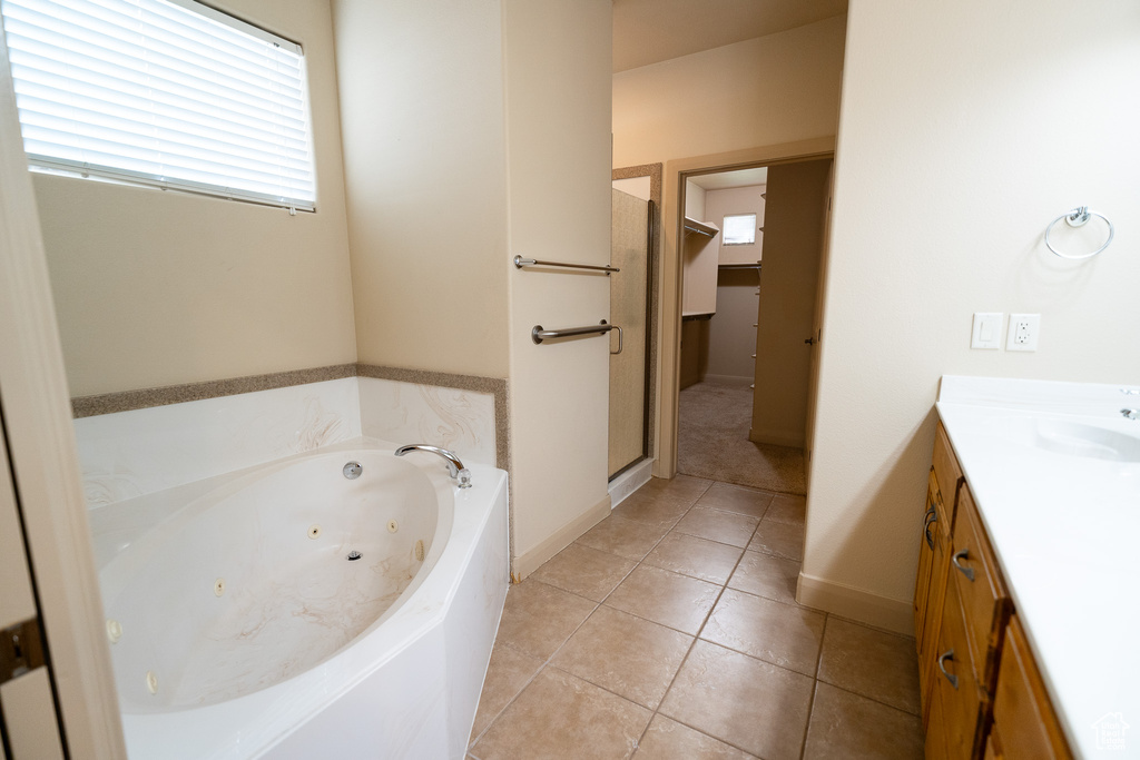 Full bathroom featuring a tub with jets, vanity, a shower stall, baseboards, and tile patterned floors
