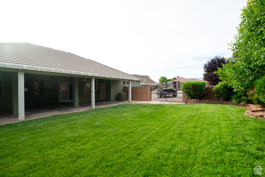 View of yard with central air condition unit, a gate, and a patio area