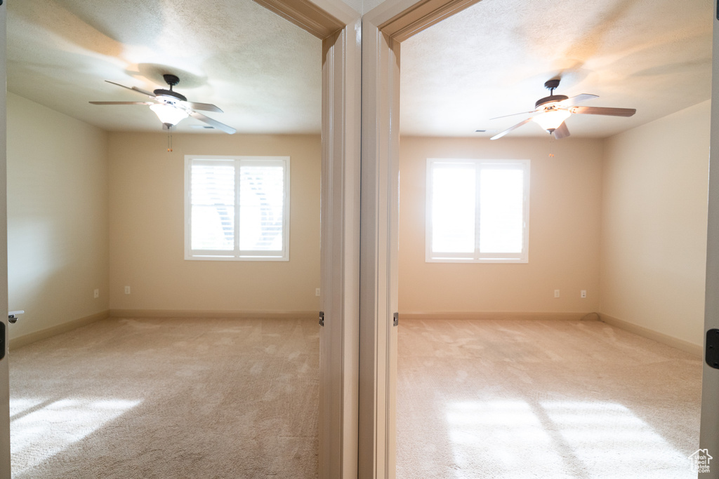 Carpeted empty room featuring a ceiling fan and baseboards