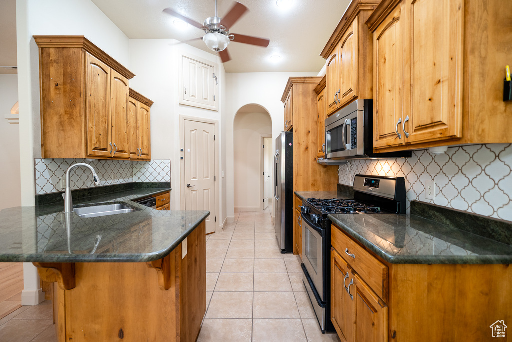 Kitchen with appliances with stainless steel finishes, a sink, a peninsula, a breakfast bar area, and light tile patterned floors