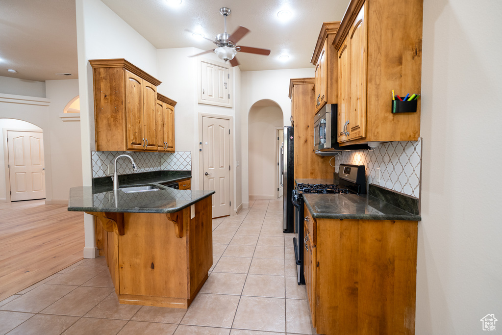 Kitchen with stainless steel appliances, arched walkways, a sink, a kitchen breakfast bar, and a peninsula