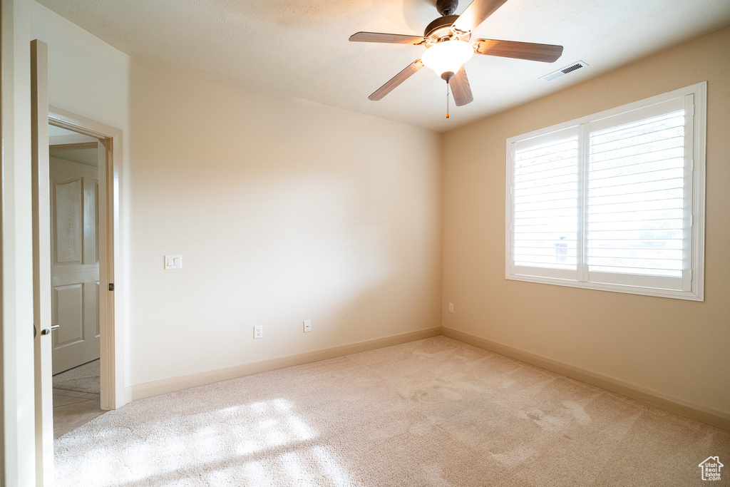 Carpeted spare room featuring ceiling fan and baseboards
