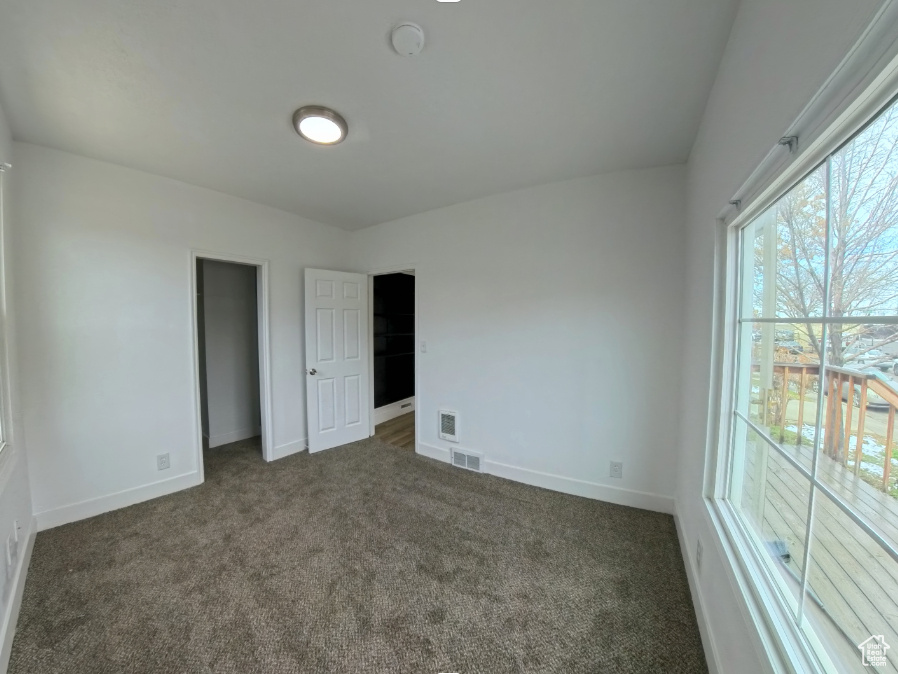 Unfurnished bedroom with dark colored carpet and baseboards