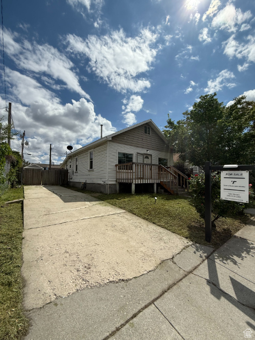 View of side of home featuring concrete driveway and a wooden deck