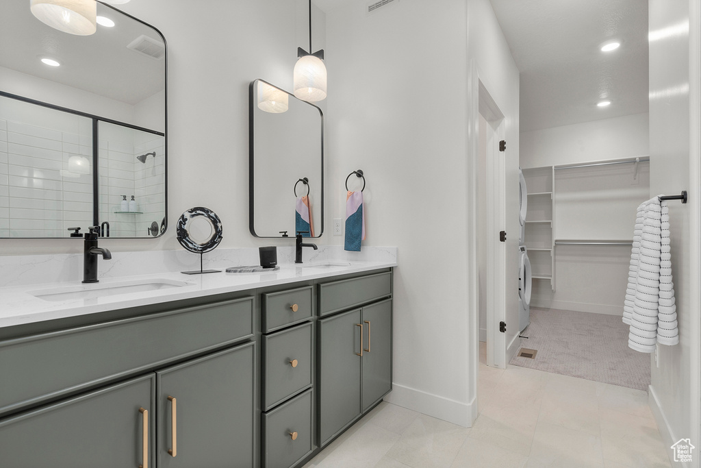 Full bathroom with double vanity, a spacious closet, tiled shower, baseboards, and recessed lighting