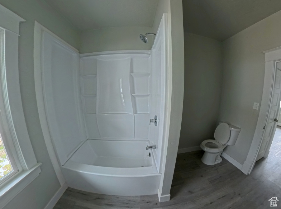 Full bath featuring baseboards, toilet, wood finished floors, and shower / tub combination