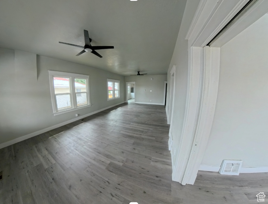 Unfurnished living room featuring ceiling fan, baseboards, and wood finished floors
