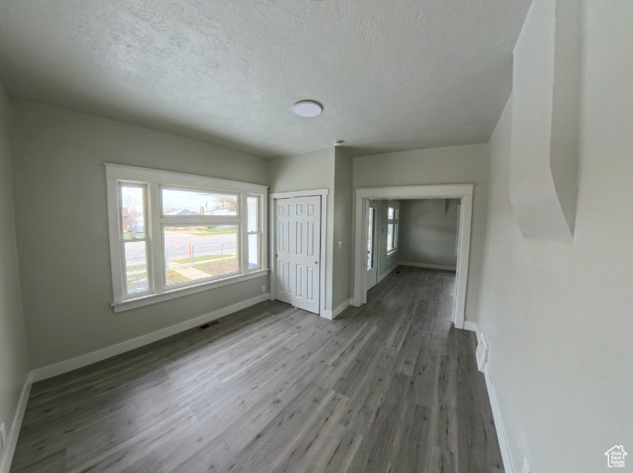 Unfurnished room with wood finished floors, baseboards, and a textured ceiling