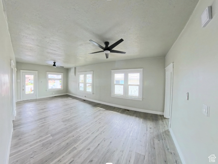 Empty room featuring a ceiling fan, baseboards, wood finished floors, and a textured ceiling