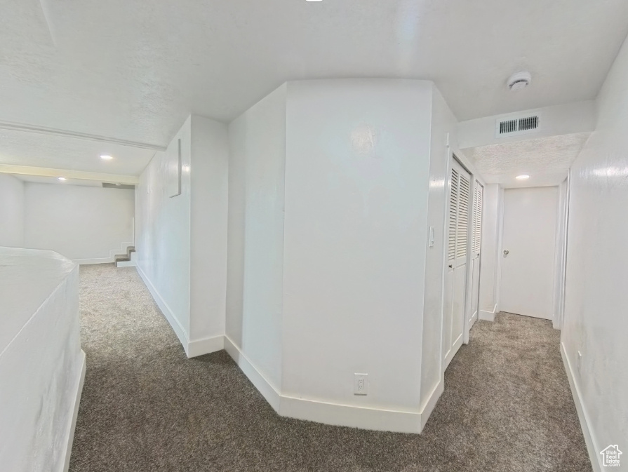 Hall with carpet flooring and baseboards