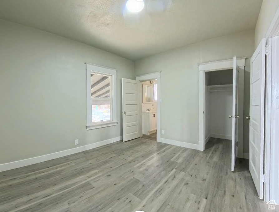 Unfurnished bedroom featuring baseboards, light wood finished floors, a closet, and a spacious closet