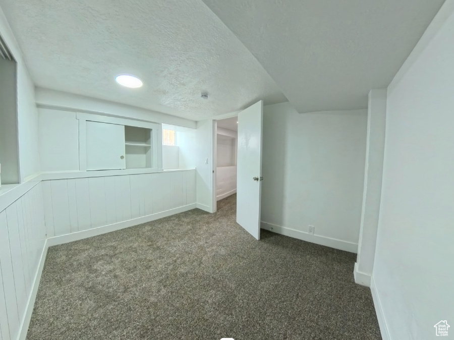 Carpeted empty room with a textured ceiling and baseboards
