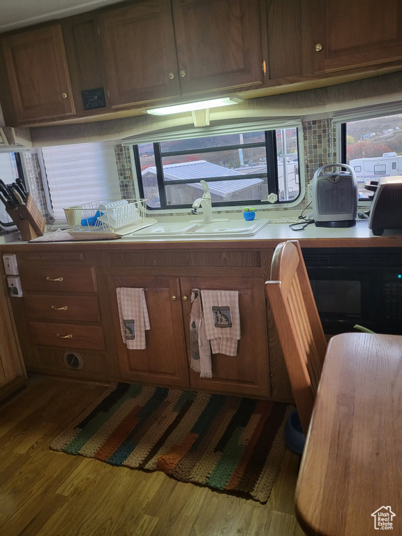 Kitchen featuring dark wood-type flooring, light countertops, black microwave, and backsplash
