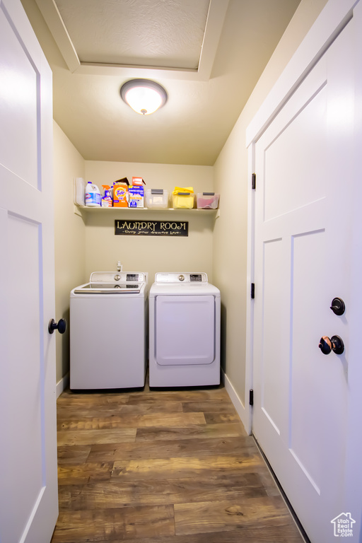 Laundry area with washing machine and clothes dryer, wood finished floors, and baseboards