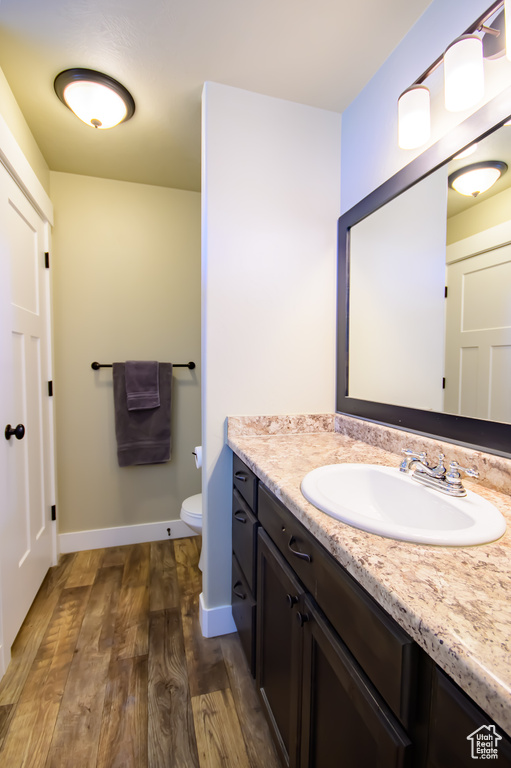 Bathroom featuring wood finished floors, vanity, toilet, and baseboards