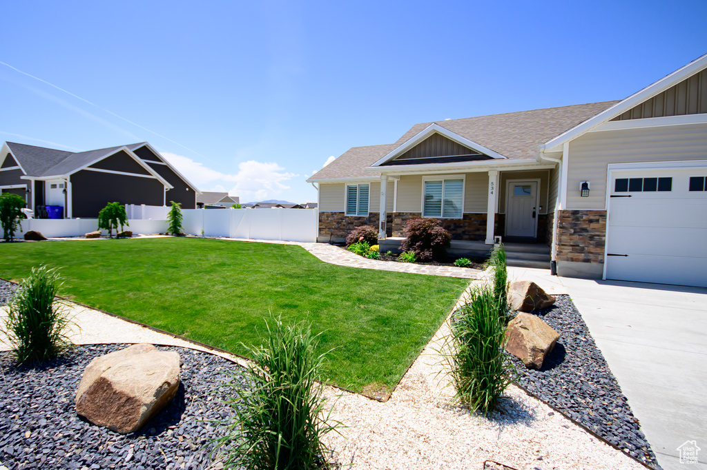 View of front of home with board and batten siding, a garage, stone siding, a shingled roof, and driveway