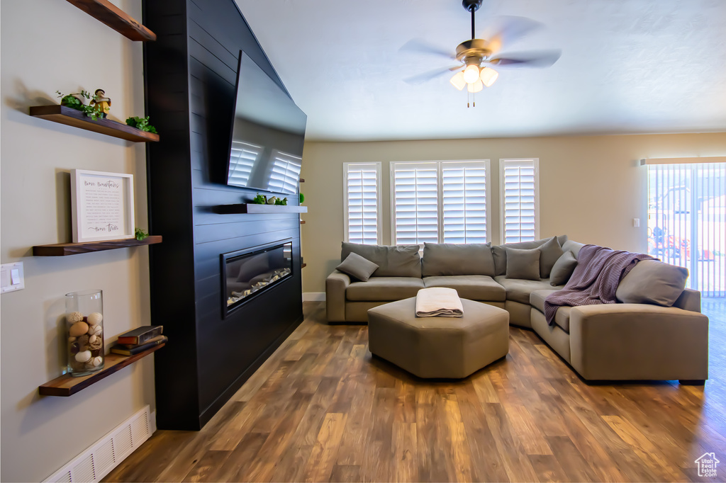 Living area with ceiling fan, a fireplace, wood finished floors, and baseboards