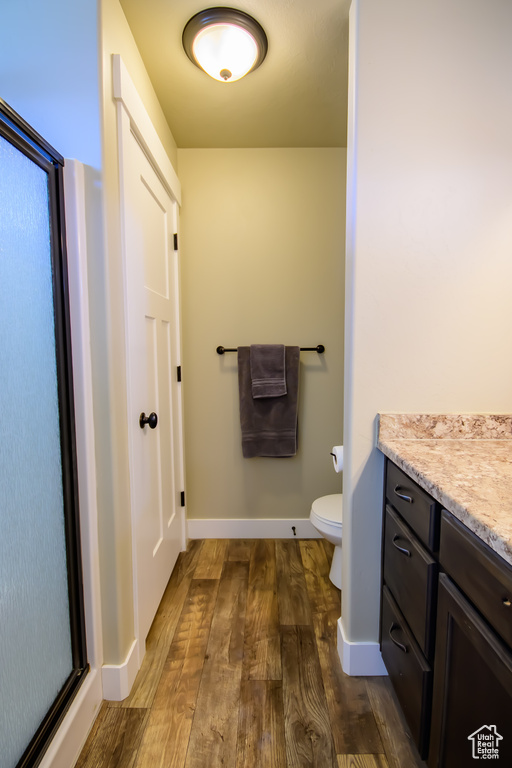 Bathroom with wood finished floors, toilet, baseboards, and vanity