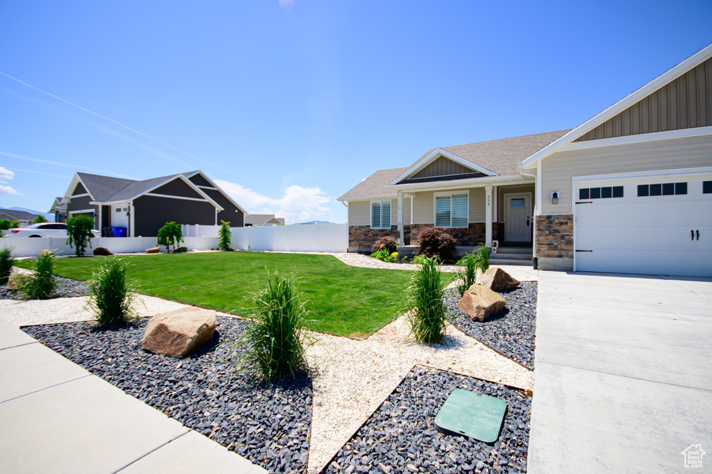View of front of home with board and batten siding, a garage, driveway, and stone siding