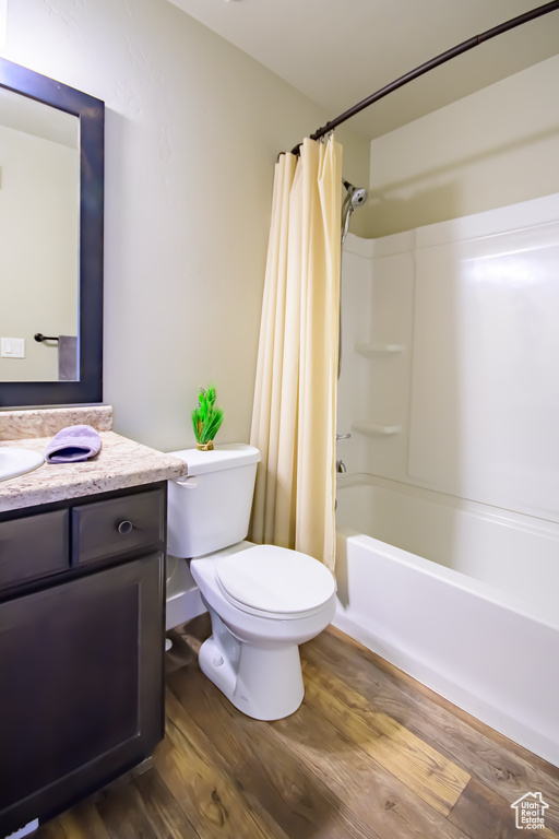 Full bathroom featuring vanity, toilet, wood finished floors, and shower / bath combination with curtain