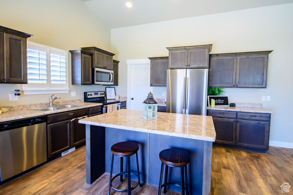 Kitchen featuring stainless steel appliances, a sink, a kitchen breakfast bar, a kitchen island, and dark brown cabinets