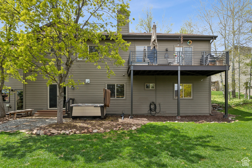 Rear view of house with a balcony, a lawn, a patio area, and a chimney