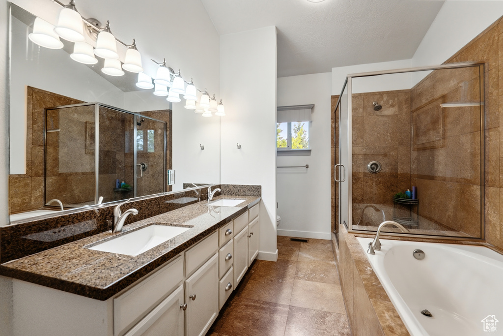 Full bathroom featuring double vanity, toilet, a garden tub, a shower stall, and baseboards