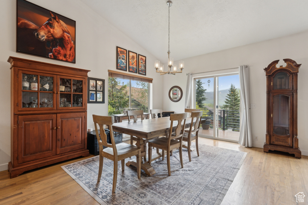 Dining room featuring a chandelier, light wood finished floors, and high vaulted ceiling