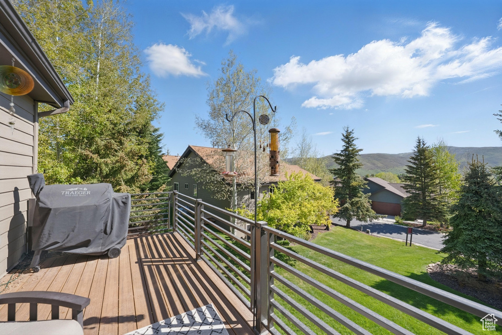 Deck with a grill, a mountain view, and a lawn