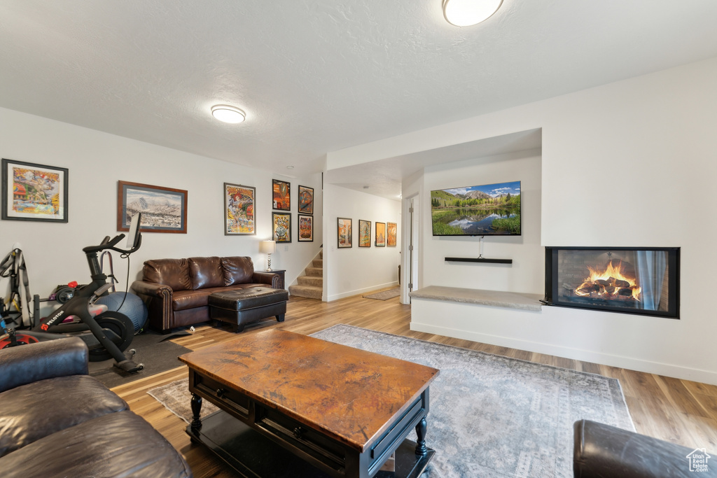 Living area with stairway, wood finished floors, baseboards, and a glass covered fireplace
