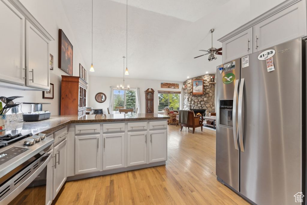 Kitchen featuring appliances with stainless steel finishes, light wood-type flooring, a ceiling fan, and a fireplace