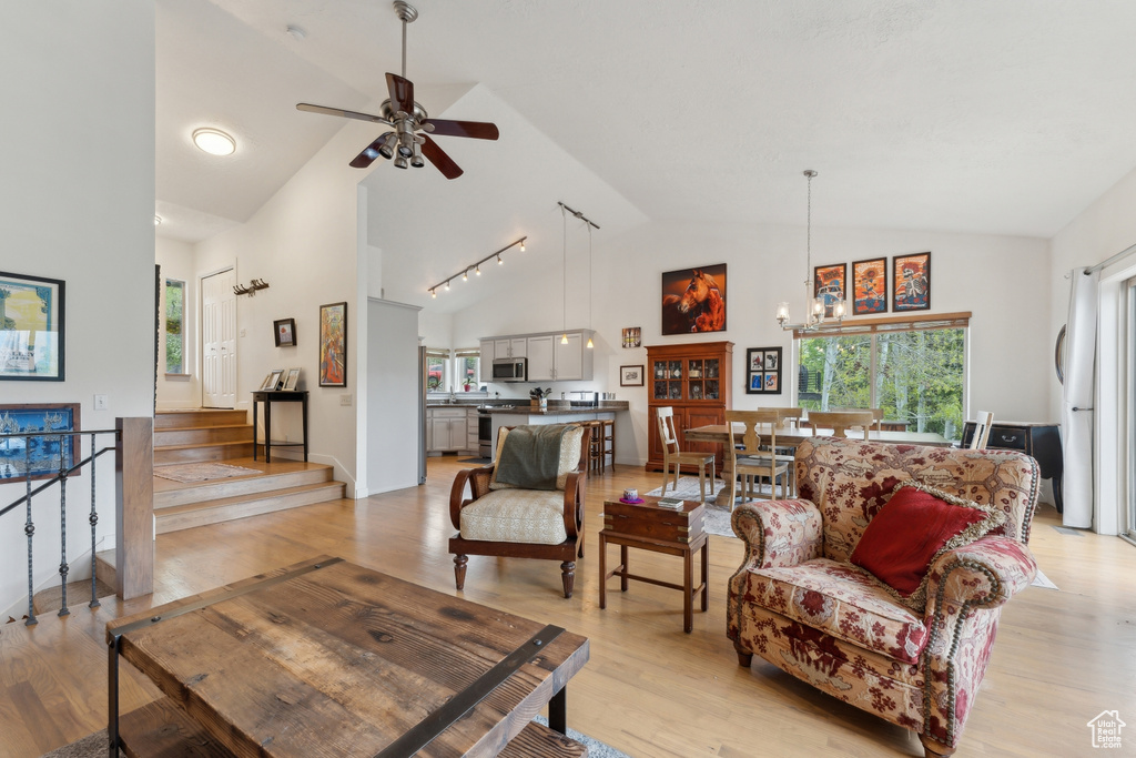 Living area featuring healthy amount of natural light, high vaulted ceiling, light wood-style floors, and ceiling fan