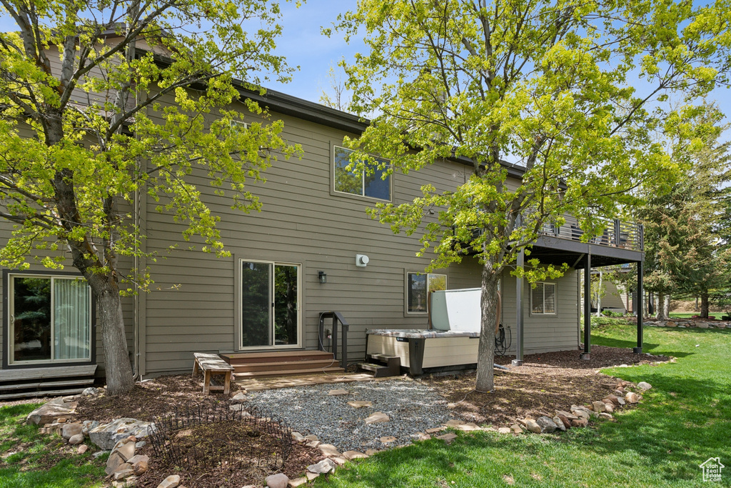 Rear view of property featuring a hot tub, a yard, and a deck