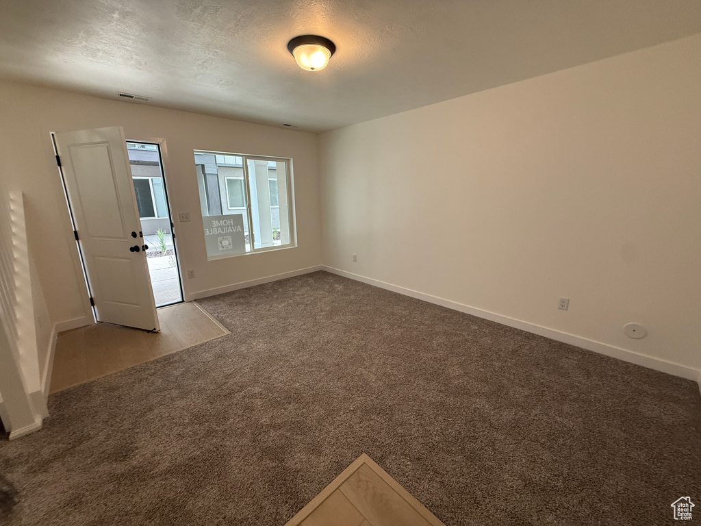 Empty room with carpet, baseboards, and a textured ceiling